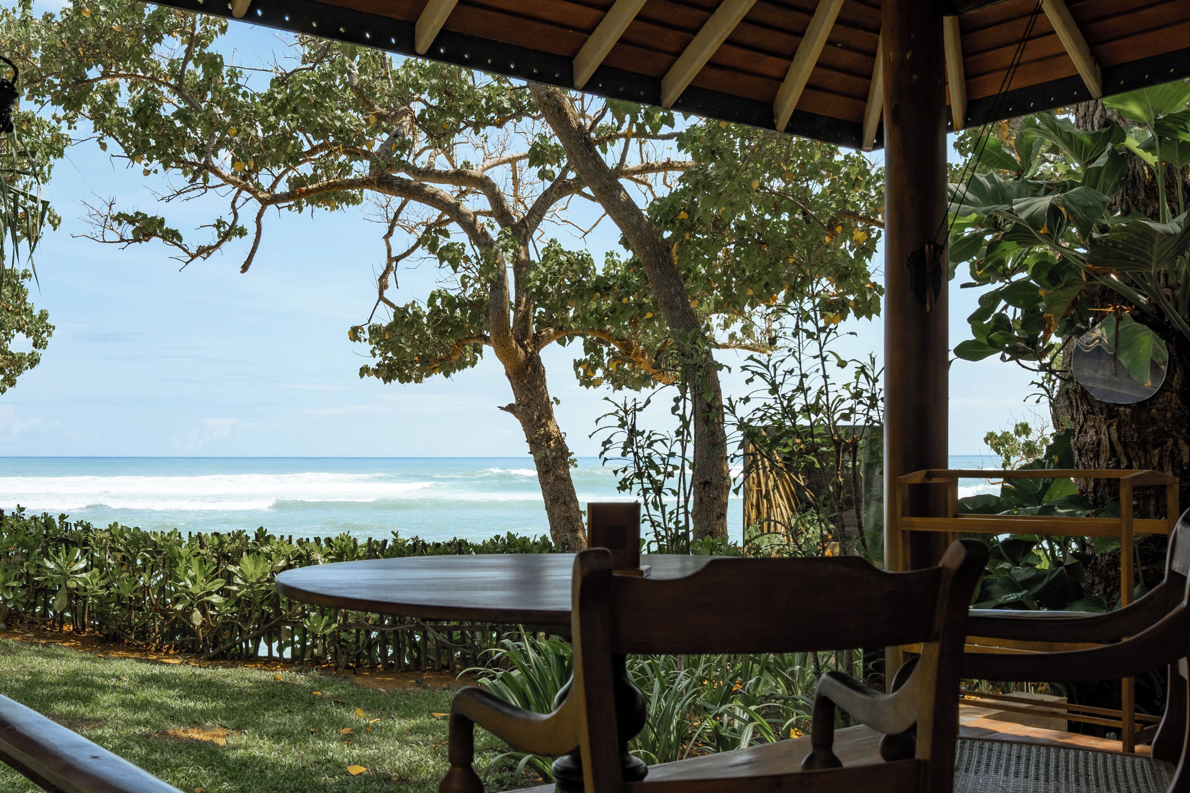 A covered outdoor seating area with a view of the ocean.