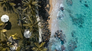 An aerial view of a beach with clear turquoise water, a rocky shoreline, and palm trees. - Eraeliya Villas & Gardens (Weligama)