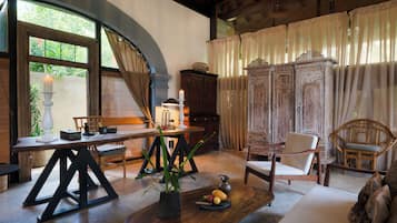 Una habitación con una mesa de madera, sillas, un armario y un ventanal con cortinas.