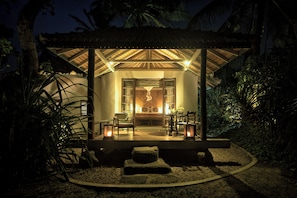 A well-lit outdoor seating area with a stone bench, chairs, and lanterns, surrounded by tropical vegetation. - Eraeliya Villas & Gardens (Weligama)