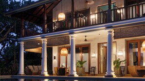 A two-story building with a balcony, columns, and a pool reflecting the structure. - Eraeliya Villas & Gardens (Weligama)