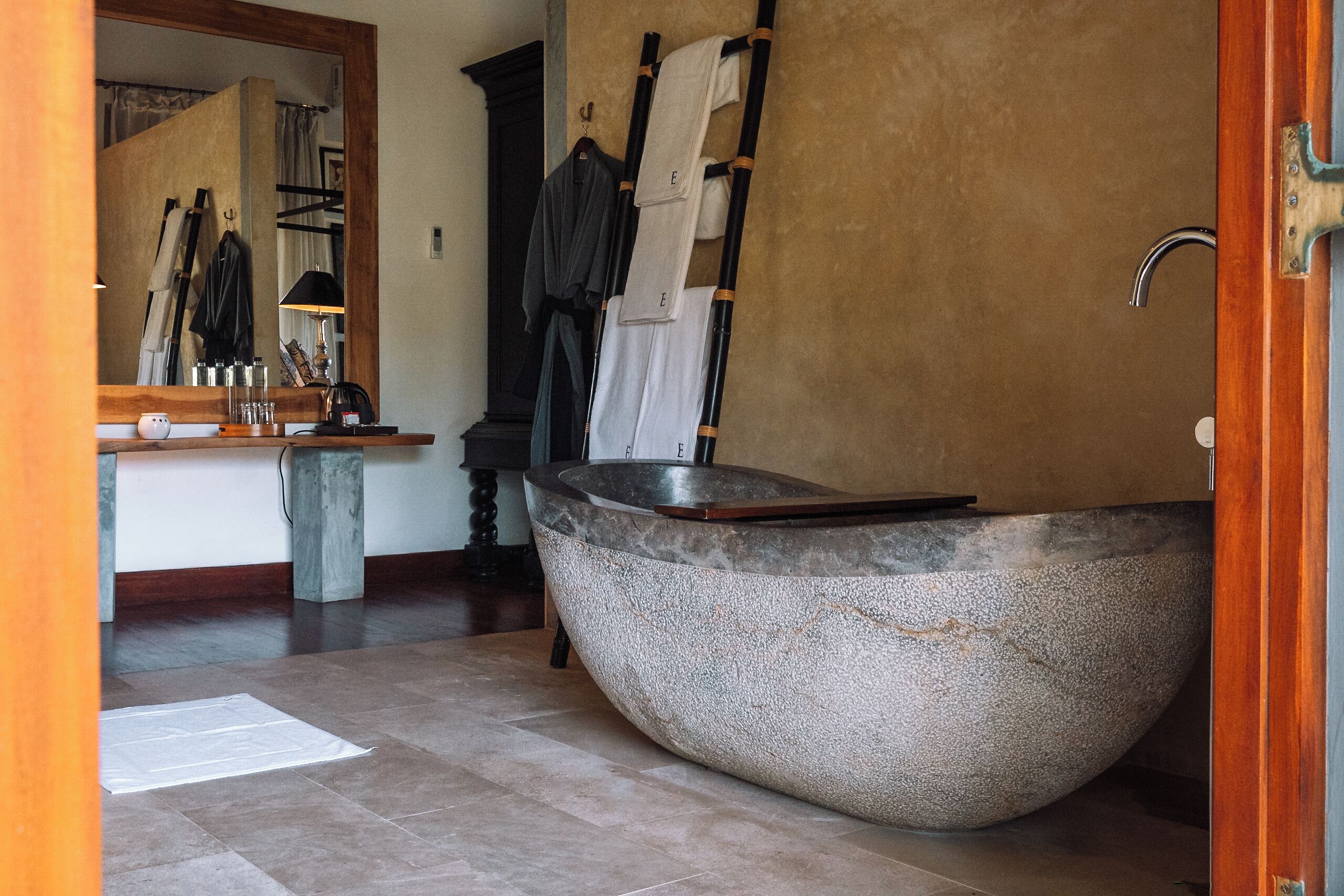 Un baño moderno con una bañera independiente grande, un tocador de madera y un espejo.
