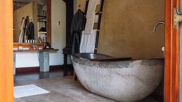 Un baño moderno con una bañera independiente grande, un tocador de madera y un espejo.