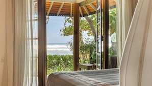 A room with a bed, a window with curtains, and a view of the ocean. - Eraeliya Villas & Gardens (Weligama)