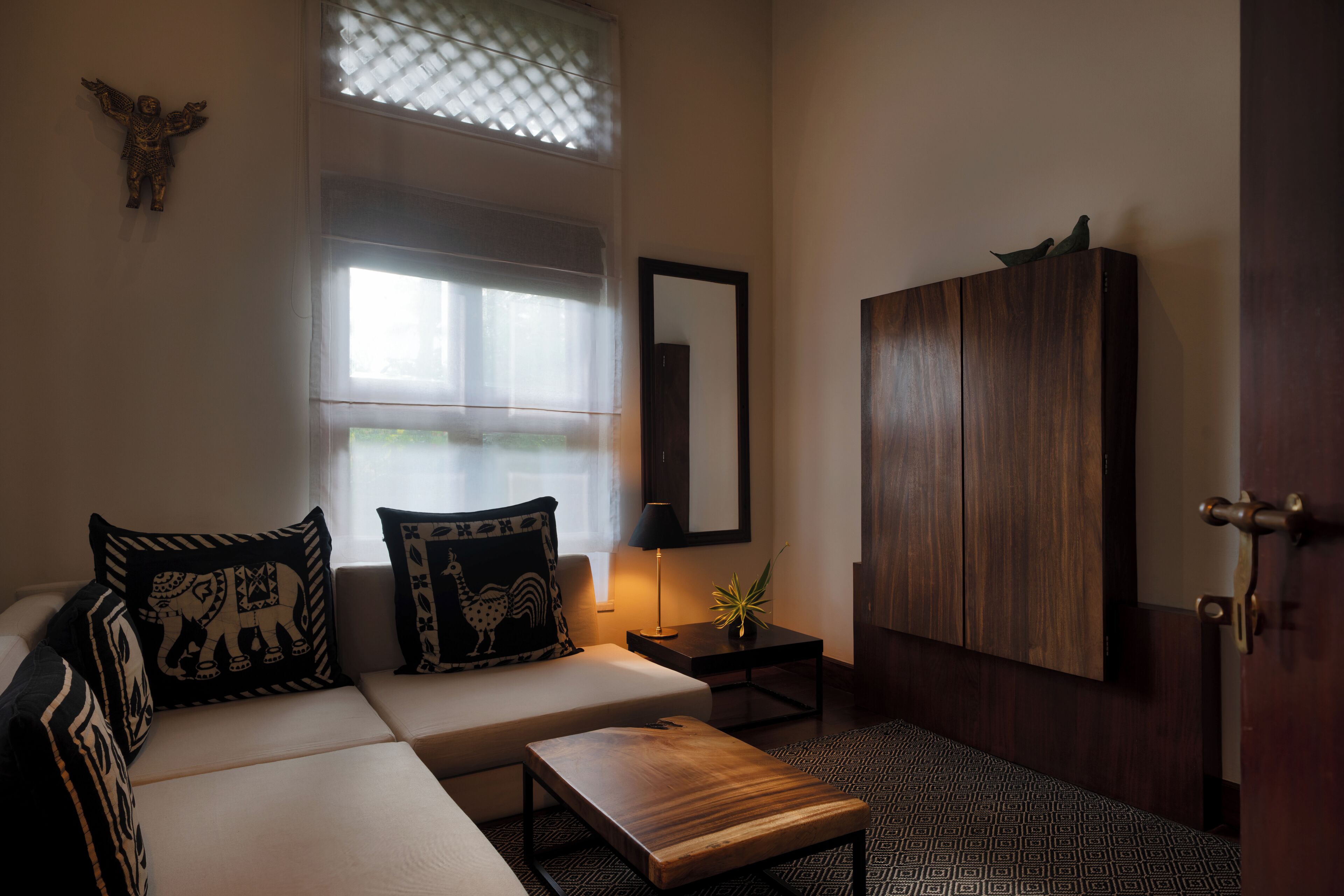 Una habitación con sofá, una mesita, lámpara, armario y ventana con persianas.