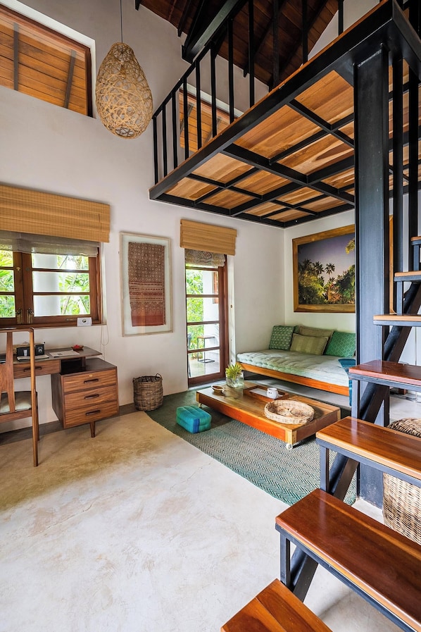 Una habitación con cama de altillo, escritorio y zona de comedor.