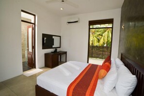 Une chambre avec un lit, un bureau, un miroir et une vue sur la verdure par la fenêtre.