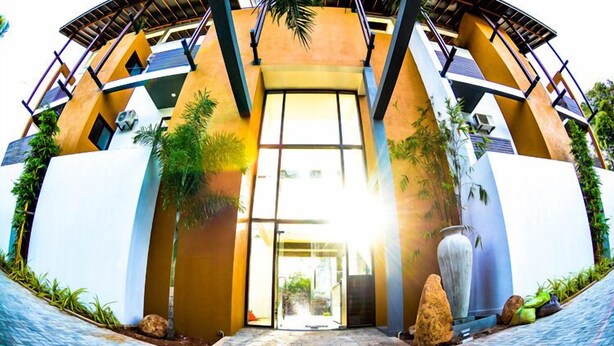 Un bâtiment moderne doté d’une entrée incurvée, de grandes fenêtres et de plantes d’extérieur.