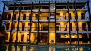 Un hôtel à plusieurs étages doté de balcons, d’une piscine et d’une façade bien éclairée.