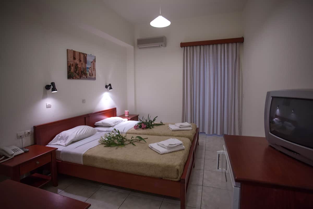 A hotel room with a bed, bedside tables, a TV, and a painting on the wall.