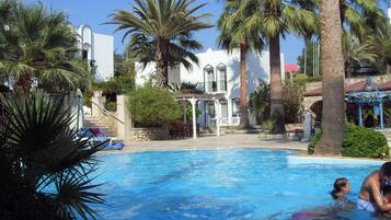 Una piscina al aire libre, sombrillas, tumbonas