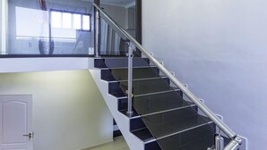 A modern staircase with glass railings and black steps, leading to an upper floor. - Discovery Guest House (Windhoek)