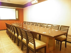 A conference room with a long table, chairs, and a projector screen. - C3 Hotel Ungaran (Ungaran)