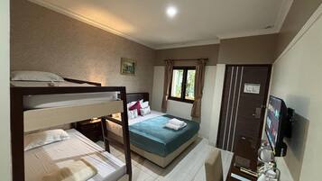 A hotel room with a bunk bed, a single bed, a desk with a computer, a TV, and a window with curtains.