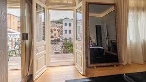 A room with a large mirror, a balcony with a view of buildings, and a door leading to an outdoor area. - 3Sixty Hotel & Suites (Nafplio)