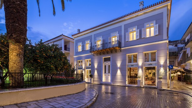 A two-story building with a bar and cafe on the ground floor, a balcony with a wrought iron railing, and a cobblestone street in front. - 3Sixty Hotel & Suites (Nafplio)