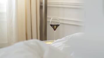 A bedside table with a glass of red wine and a lamp.