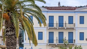 A building with multiple windows and balconies, a palm tree, and a wrought iron fence. - 3Sixty Hotel & Suites (Nafplio)