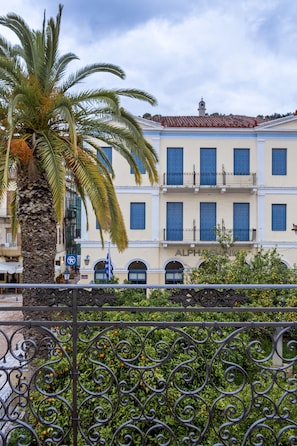 A building with multiple windows and balconies, a palm tree, and a wrought iron fence. - 3Sixty Hotel & Suites (Nafplio)