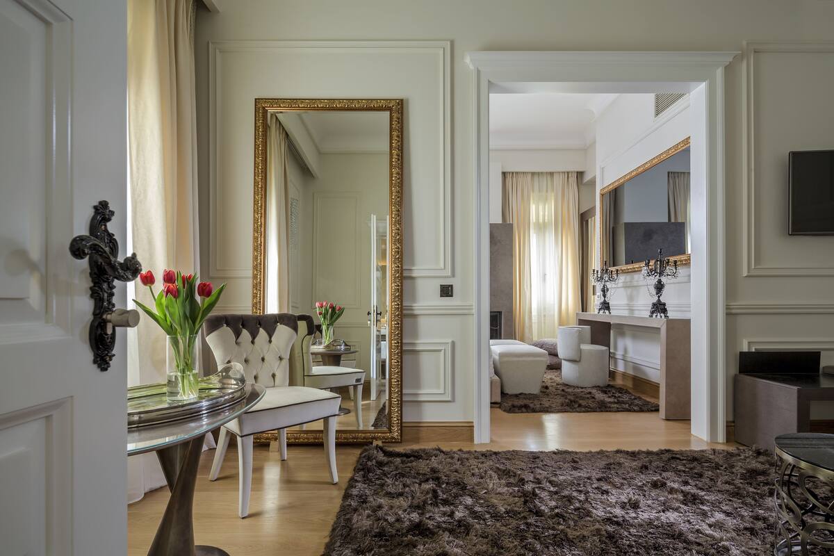 Un salon spacieux agrémenté d’un grand miroir, d’un canapé capitonné et d’une cheminée moderne.