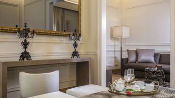 Habitación de hotel con un espejo grande, una araña, un sofá, una bandeja con vajilla para té y una mesita de noche con una lámpara.