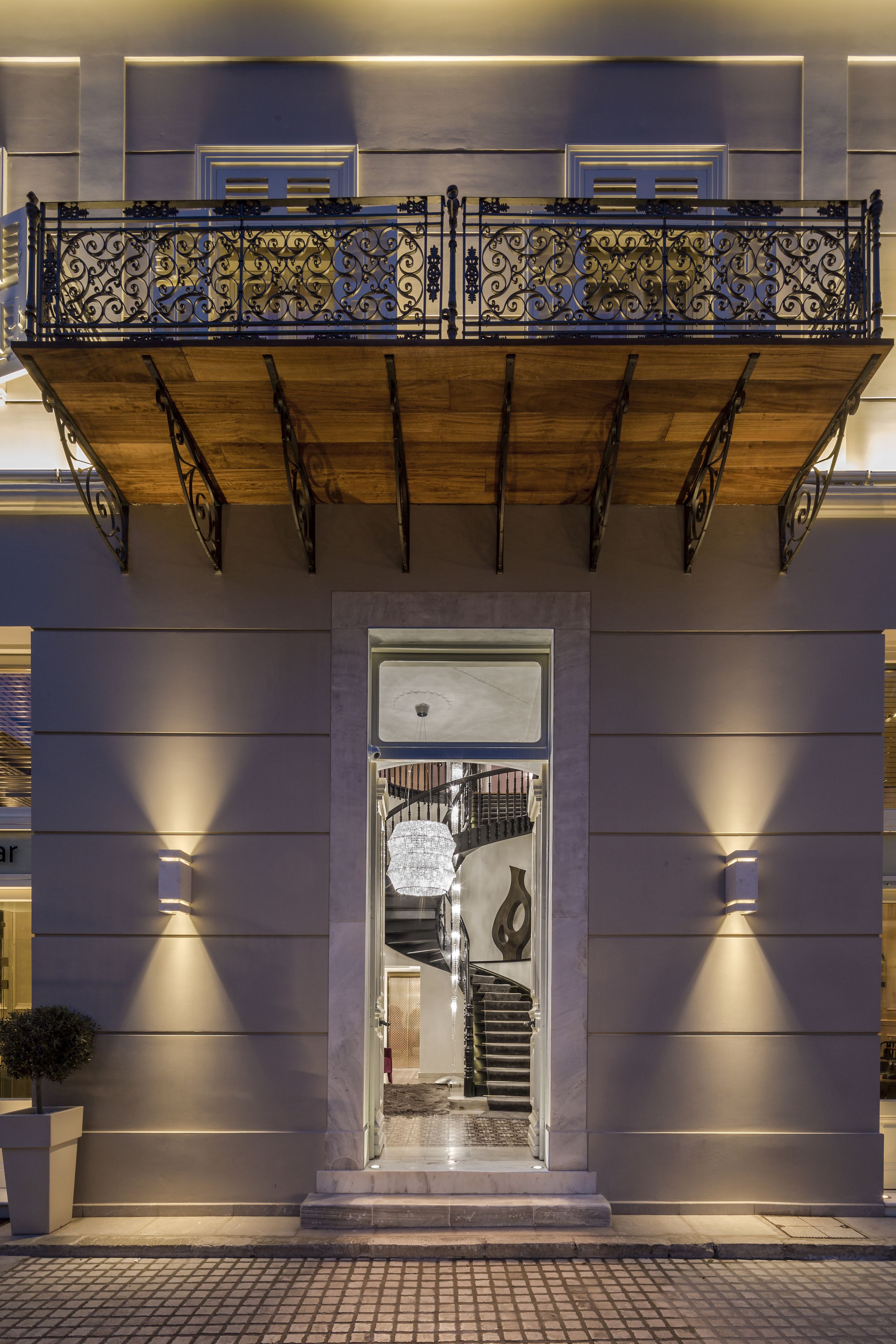 A building with a balcony, a staircase, and a door with a light fixture.
