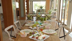 A dining area with a long wooden table set for a meal, surrounded by chairs. - The Corner Hotel (Bodrum)