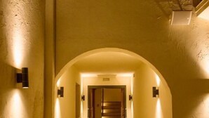 A hotel hallway with a checkered floor, arched ceiling, and wall-mounted lighting. - The Corner Hotel (Bodrum)
