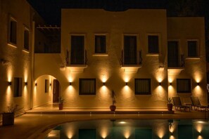 Zona junto a la piscina con piscina, plantas en macetas y sillones de descanso.