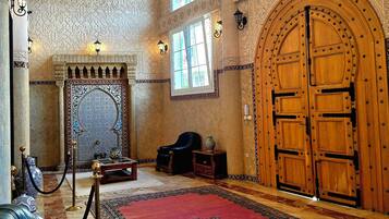 Un intérieur comprenant une grande porte en bois, un lustre et un tapis à motifs.