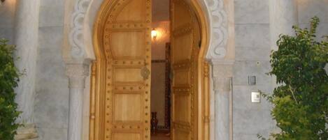 A grand wooden door with intricate metal detailing, set within a stone archway.
