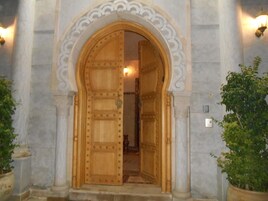 Una puerta de madera imponente con detalles metálicos intrincados, ubicada en un arco de piedra.