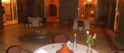 Un comedor con mesas redondas, sillas, un cuenco decorativo central y una tagine marroquí.