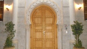 A large wooden door with a decorative arch above it, flanked by two potted plants.