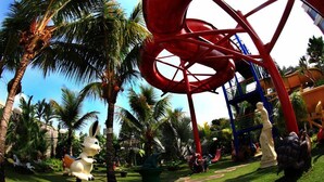 A theme park with a red water slide, palm trees, and various statues. - Grand Wahid Hotel Salatiga (Salatiga)