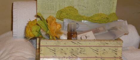 A neatly arranged gift box with a bottle of lotion and a yellow flower on a white towel.