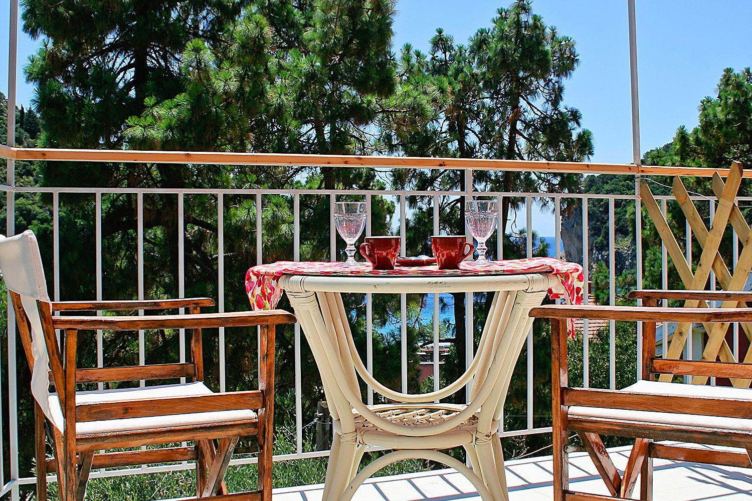 Un patio al aire libre con una mesa preparada para dos personas, rodeado de sillas de madera.