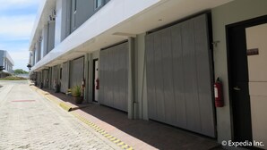 Ein modernes Gebäude mit geschlossenen Garagentoren, einem Feuerlöscher und einem Blumentopf auf dem Bürgersteig.