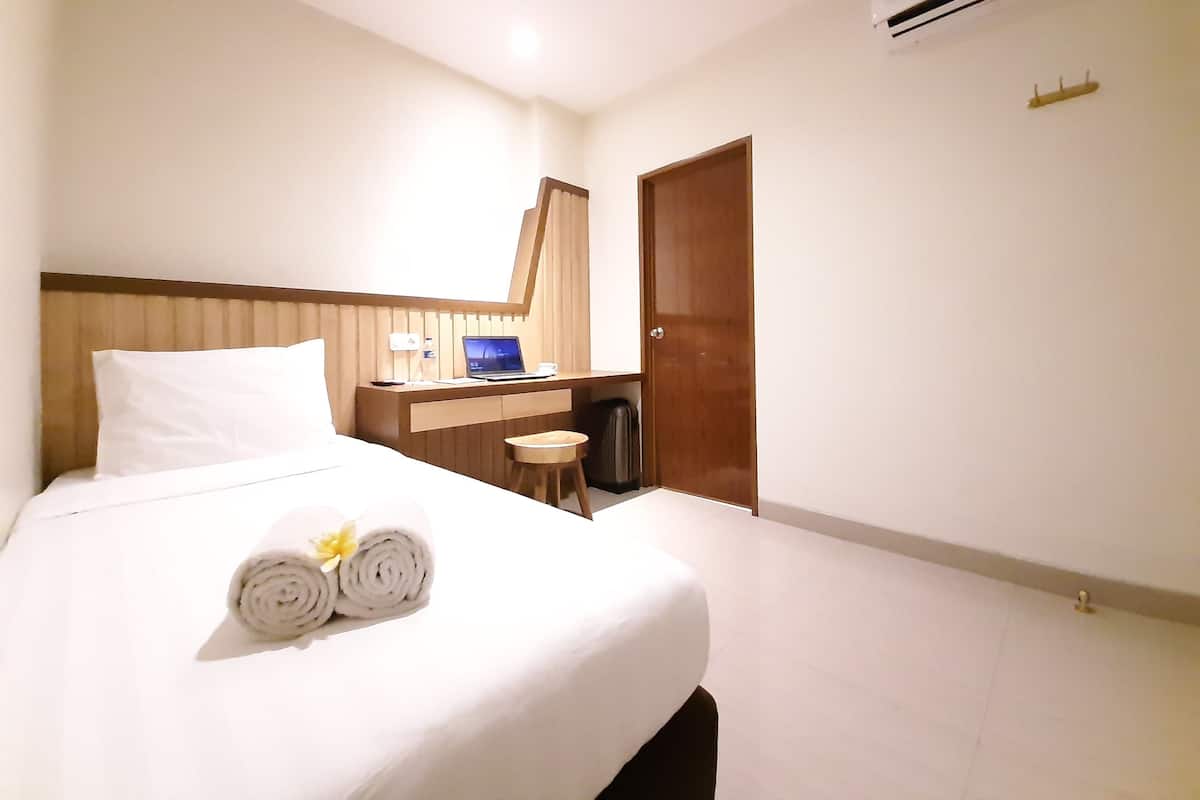Hotellihuone, jossa on sänky, työpöytä, kannettava tietokone ja ilmastointilaite.
