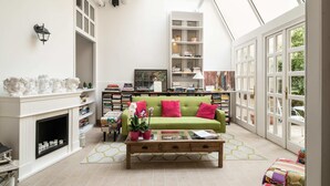 A bright living room with a green sofa, a fireplace, and a large window. - Cas'E Charming House (Caserta)