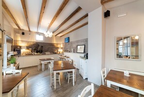 Una cocina amplia con vigas de madera, una zona de comedor con sillas blancas y un ventanal grande.