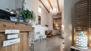 A hotel reception area with wooden decor, a chandelier, and a sign indicating a hotel booking service. - Cas'E Charming House (Caserta)