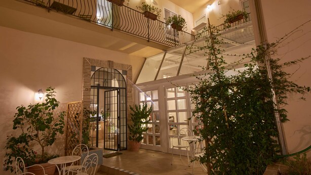 A multi-level atrium with a glass ceiling, potted plants, and a seating area with chairs and a table. - Cas'E Charming House (Caserta)