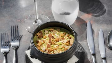 Une table à manger avec un bol de soupe, un verre de vin blanc et un verre d’eau.