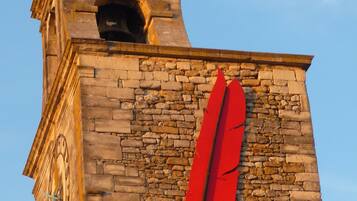Une tour historique, dotée d’une horloge et ornée d’une sculpture en forme de plume rouge.