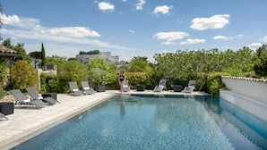 Piscina com espreguiçadeiras e uma pessoa caminhando em direção à piscina.