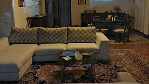 A living room with a sofa, coffee table, and a view of a garden with a door and a staircase. - B&B da Ronald...a Pian del Papa (Pratovecchio Stia)