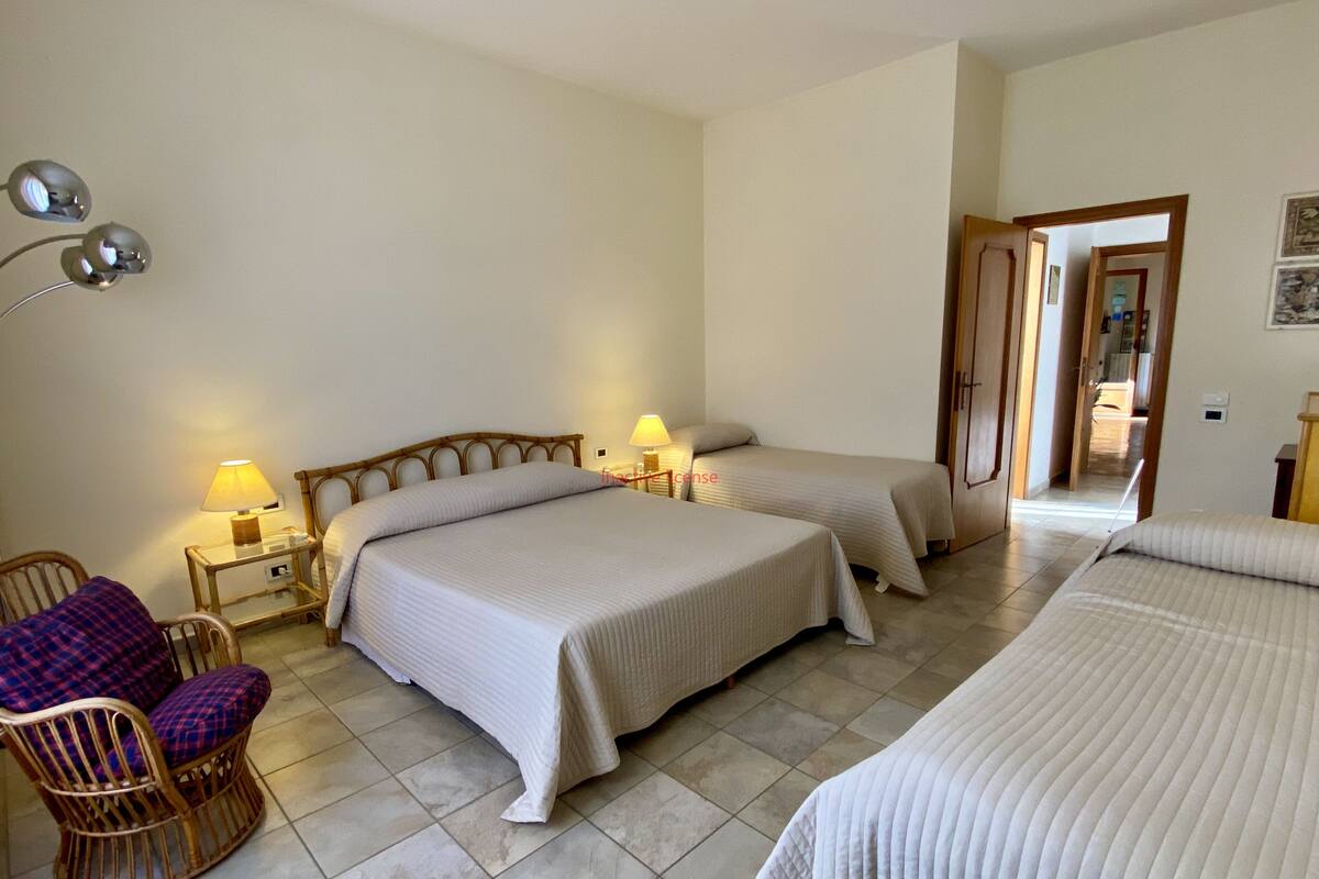 A hotel room with two beds, a chair, and a nightstand with lamps.
