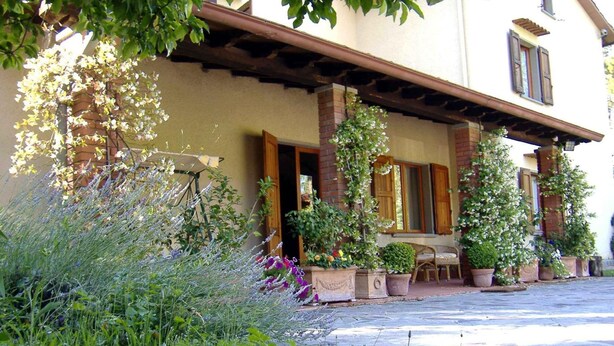A building with a covered porch, potted plants, and a bench. - B&B da Ronald...a Pian del Papa (Pratovecchio Stia)