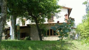 A rustic house with a stone facade, a balcony, and a garden with red roses. - B&B da Ronald...a Pian del Papa (Pratovecchio Stia)